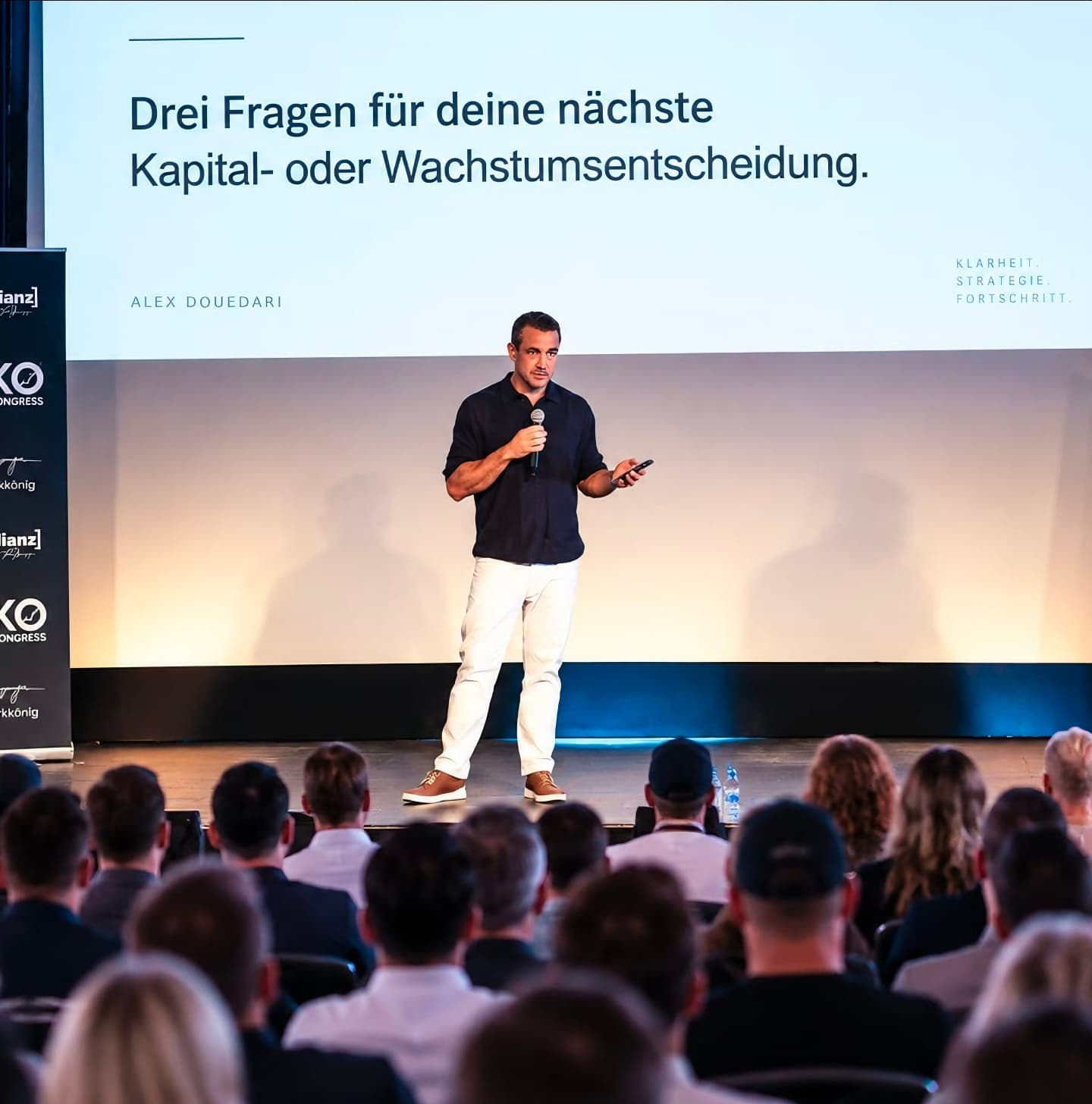 Alex Douedari spricht auf einer Bühne vor Publikum über Kapital- und Wachstumsentscheidungen